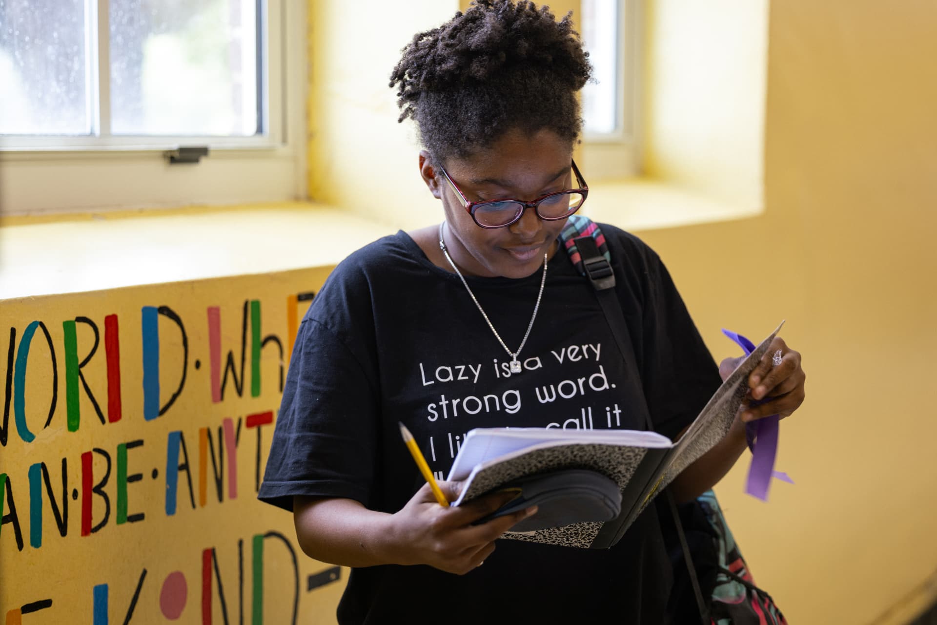 A PHMS student writing in a notebook in front of an inspirational mural
